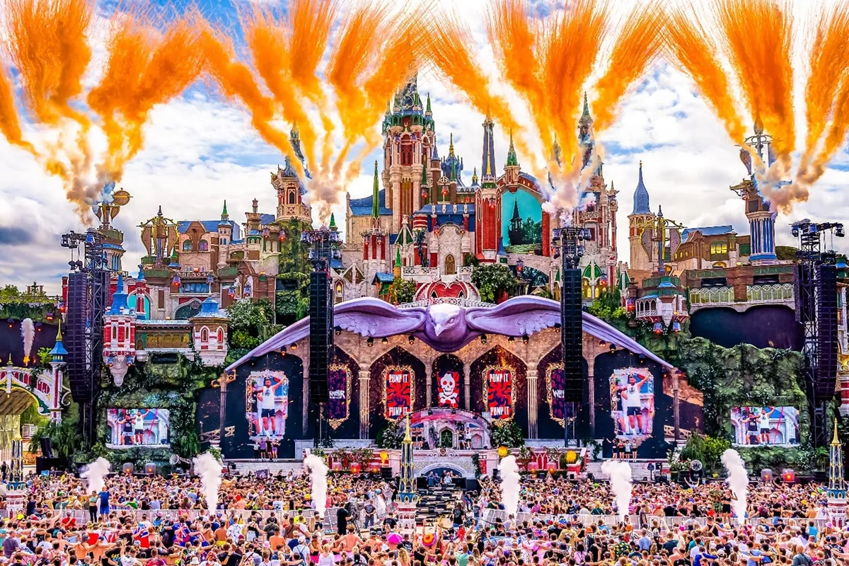 Palco principale del Tomorrowland con scenografia da castello fiabesco, fuochi d’artificio arancioni e folla di spettatori.