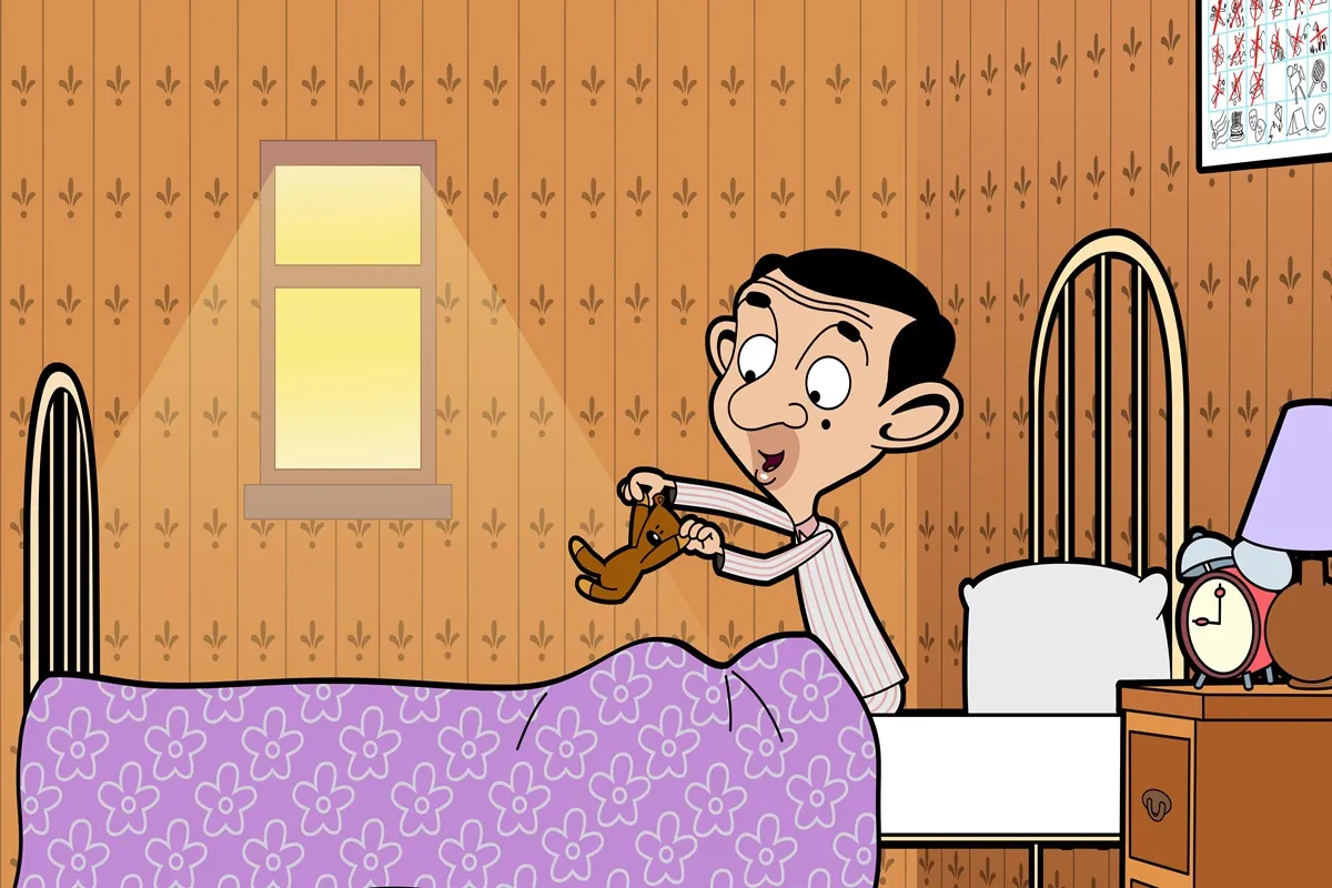 Mr. Bean versione animata che gioca felice con il suo orsacchiotto Teddy nella camera da letto, illuminata dalla luce del sole che entra dalla finestra.