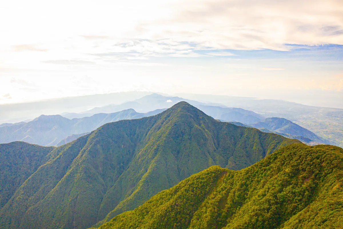 Veduta aerea delle Blue Mountains in Giamaica con colline verdeggianti e cielo luminoso, simbolo del turismo sostenibile e patrimonio UNESCO