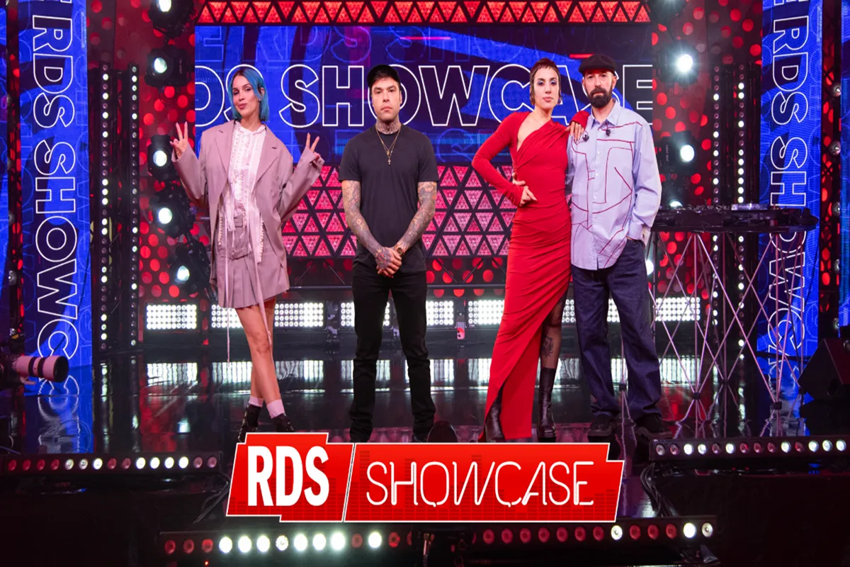 Artisti e ospiti del RDS Showcase posano sul palco illuminato con scenografia rossa e blu, davanti al logo dell’evento