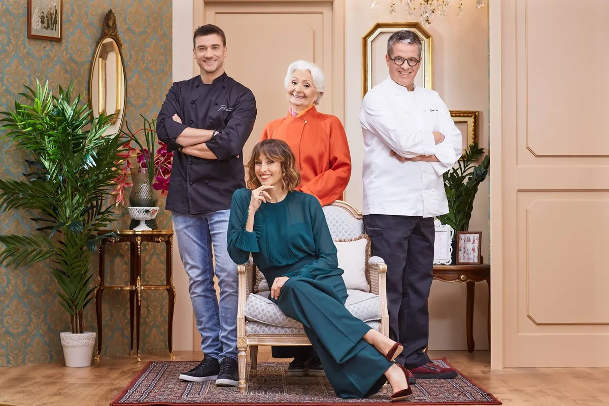 Brenda Lodigiani seduta su una poltrona, sorridente, con i giudici di Bake Off Italia – Dolci in Forno in piedi dietro di lei