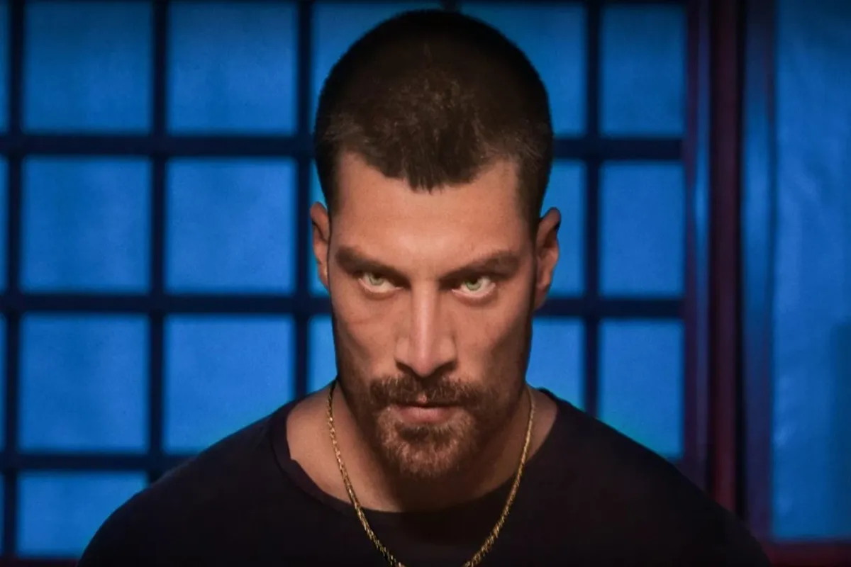 Primo piano di Simone Susinna con sguardo penetrante, sfondo blu con griglia luminosa