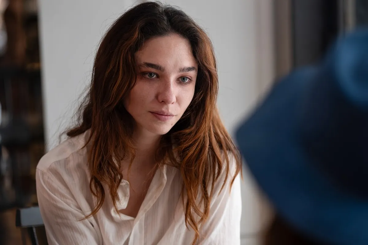 Primo piano di Matilda De Angelis con camicia bianca, sguardo intenso e capelli leggermente mossi, in una scena del film “Fuori”.