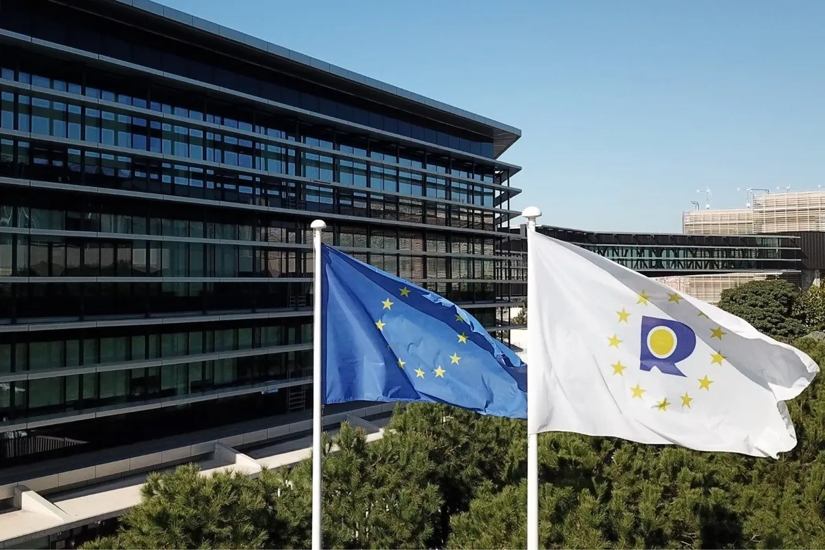 Bandiere dell'Unione Europea e della Banca Centrale Europea sventolano davanti a un moderno edificio, simbolo di istituzioni europee.