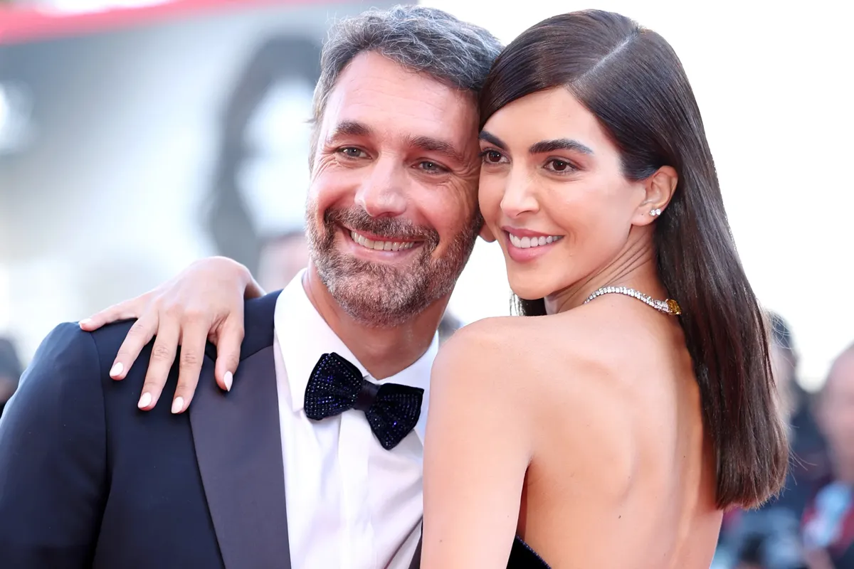 Raoul Bova in frac e papillon accanto a Rocío Muñoz Morales in elegante abito senza spalline, entrambi sorridenti e abbracciati sul red carpet