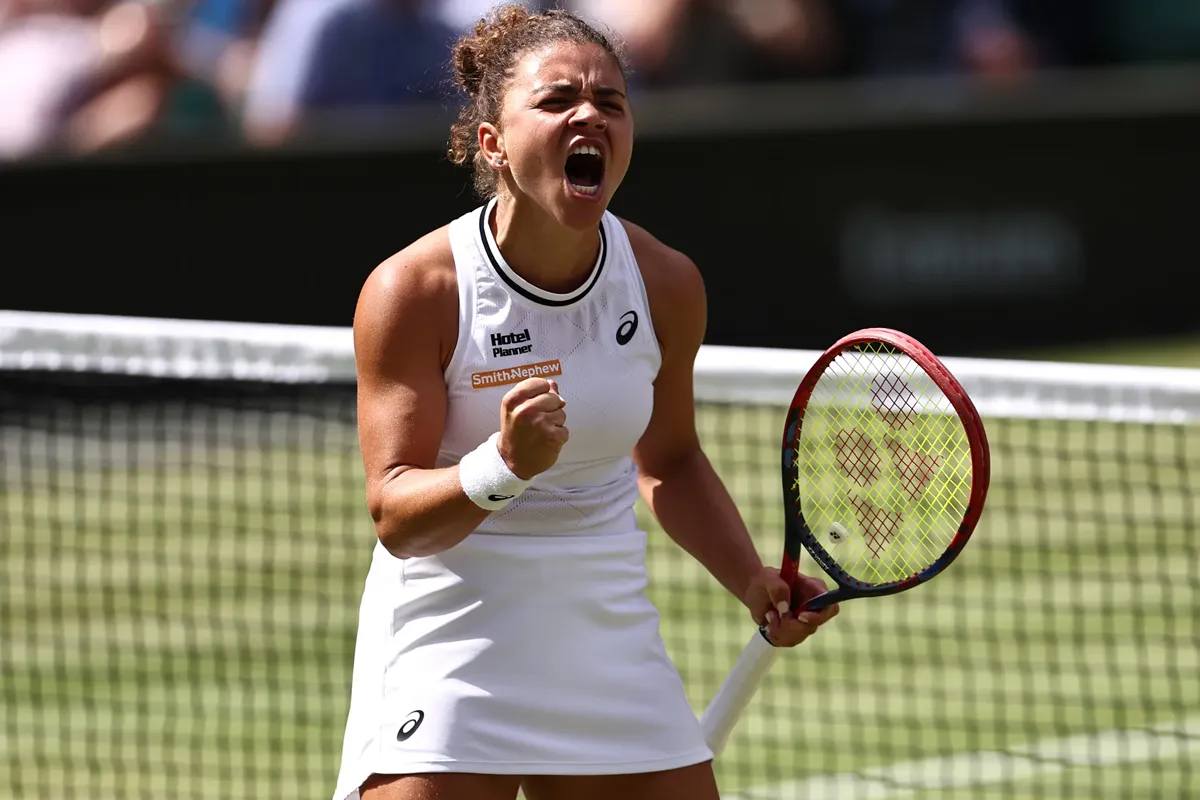 La tennista Jasmine Paolini urla di gioia stringendo il pugno dopo un punto vinto a Wimbledon, impugnando la racchetta con decisione