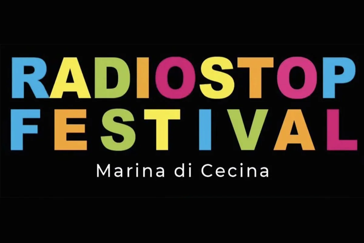 Logo RadioStop Festival”: scritta “RADIOSTOP FESTIVAL” a caratteri maiuscoli colorati (azzurro, giallo, verde, rosa, arancio) su sfondo nero, con sottotitolo bianco “Marina di Cecina” al centro
