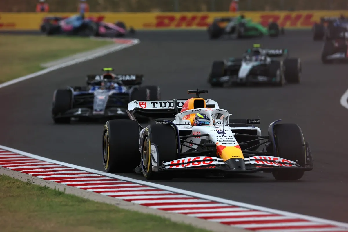 Monoposto di Formula 1 Red Bull Racing in pista durante una gara, seguita da altre vetture sul circuito.