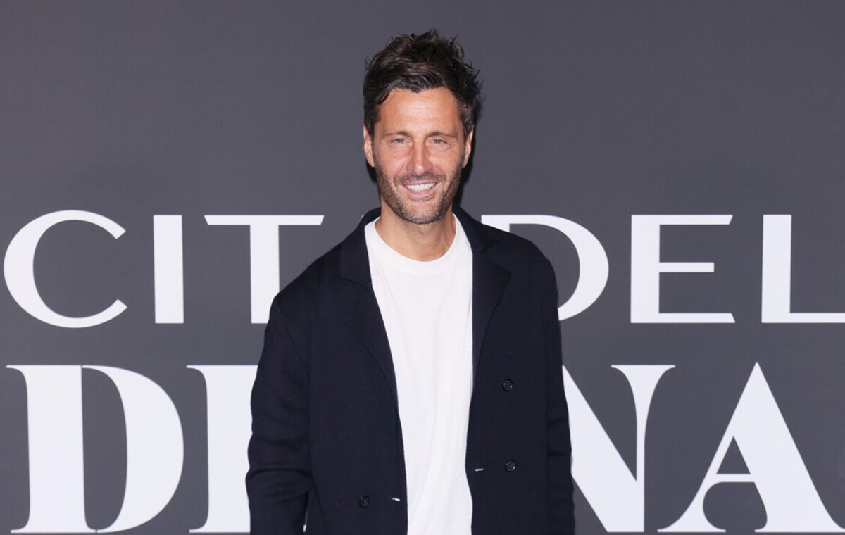 Alessio Loparco in posa sul red carpet, sorridente, con giacca scura e t-shirt bianca, durante un evento pubblico