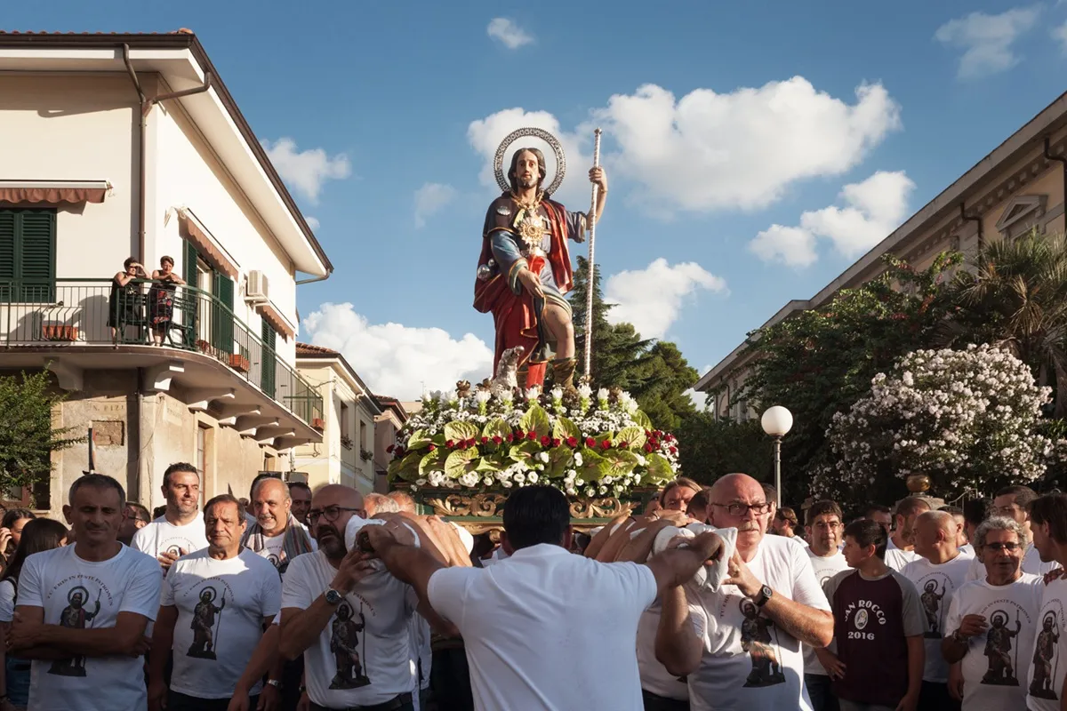 Fedeli portano in processione la statua di San Rocco addobbata con fiori durante la festa patronale in Calabria