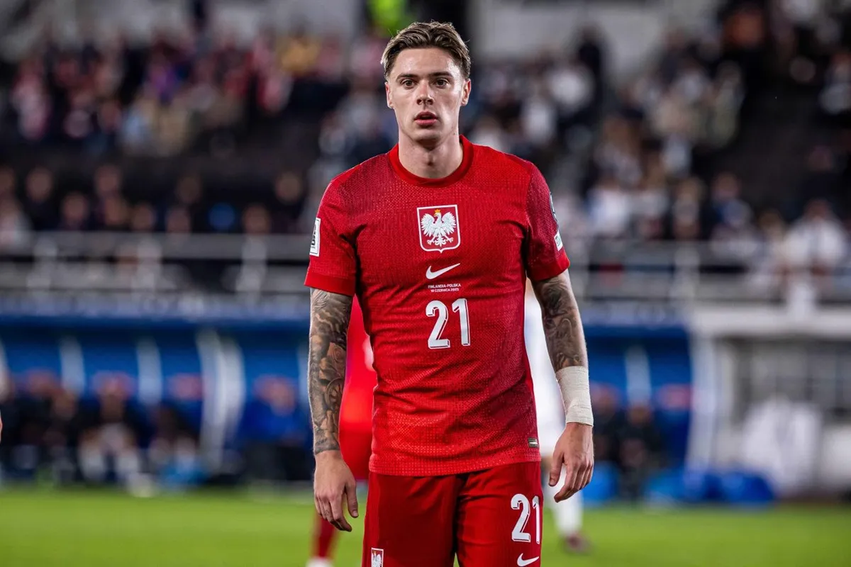 Nicola Zalewski con la maglia rossa della nazionale polacca durante una partita, concentrato in campo