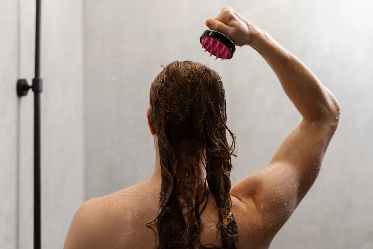 Massaggio del cuoio capelluto sotto la doccia con spazzola in silicone