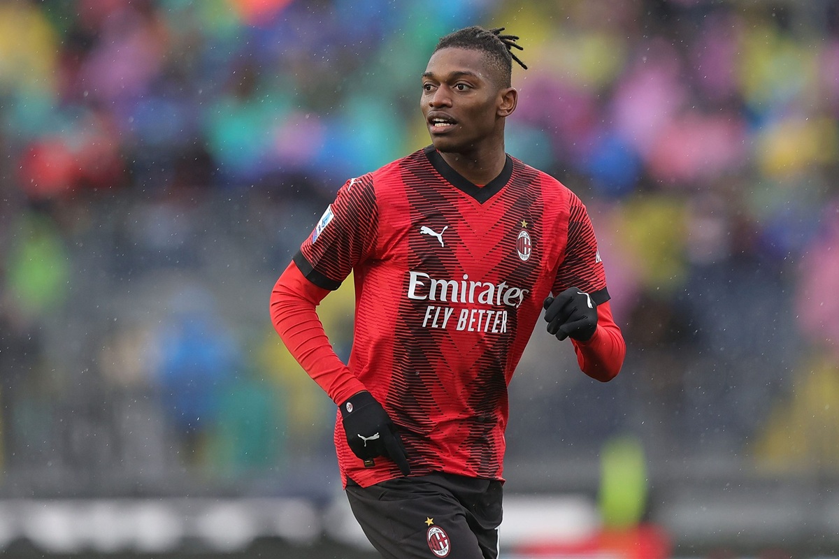 Calciatore del Milan, Rafael Leão, corre in campo indossando la maglia rossonera durante una partita sotto la pioggia.