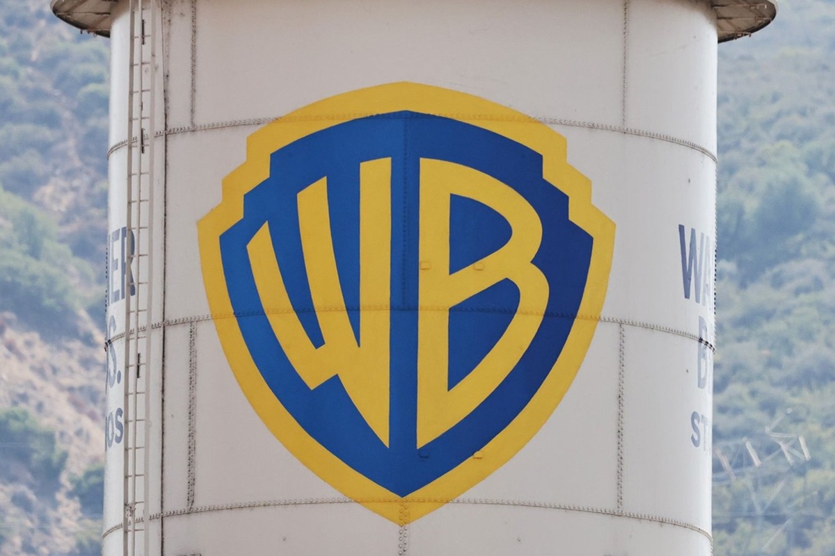 Logo blu e giallo della Warner Bros dipinto sul famoso Water Tower degli studi cinematografici, con colline sullo sfondo.