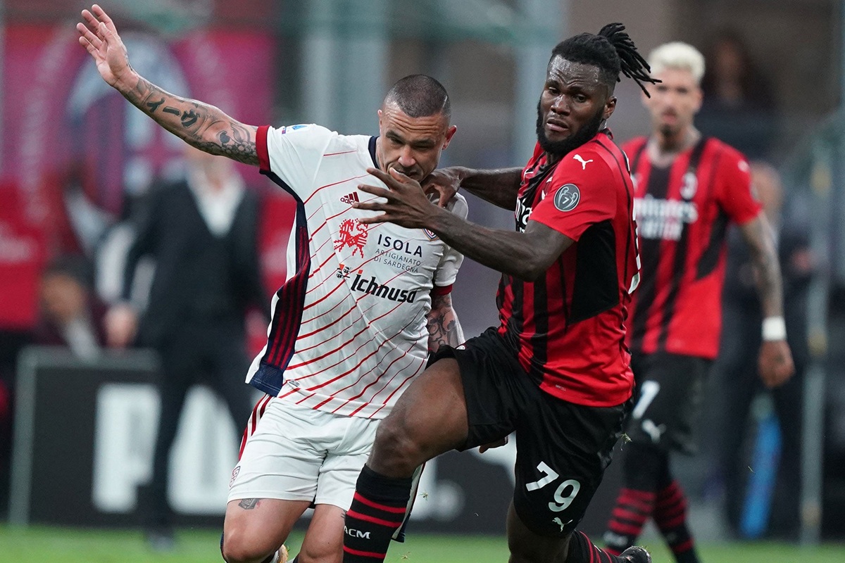 Giocatore del Cagliari in maglia bianca e giocatore del Milan in maglia rossonera lottano per il pallone durante una partita di Serie A