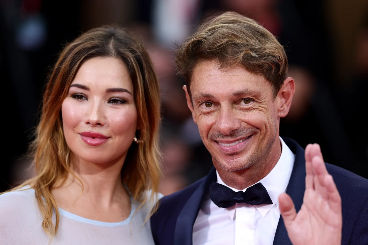 Uomo in smoking con papillon e donna in abito elegante posano sorridenti sul red carpet durante una cerimonia cinematografica internazionale.