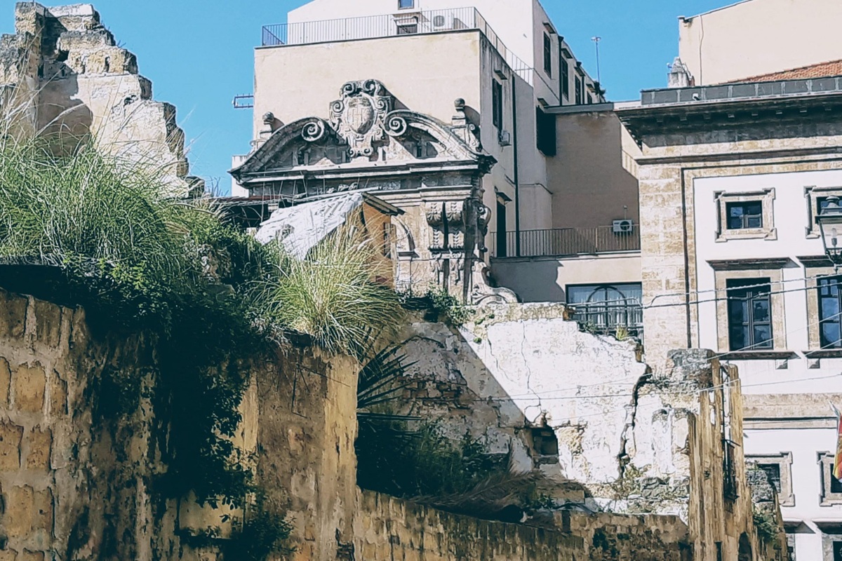 Rovine di edifici storici a Palermo con muri crollati, vegetazione spontanea e strutture antiche in un contesto urbano.