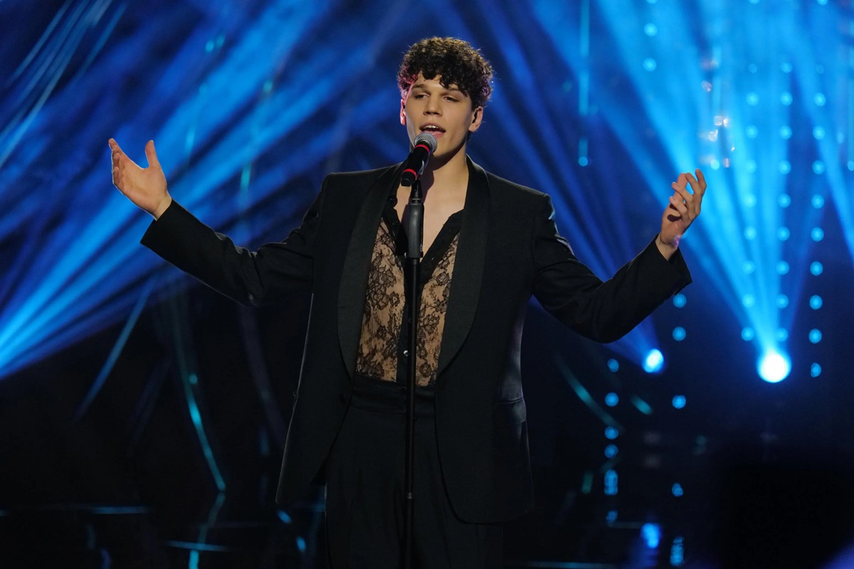 Giovane cantante che si esibisce al Festival di Sanremo sul palco illuminato con luci blu scenografiche