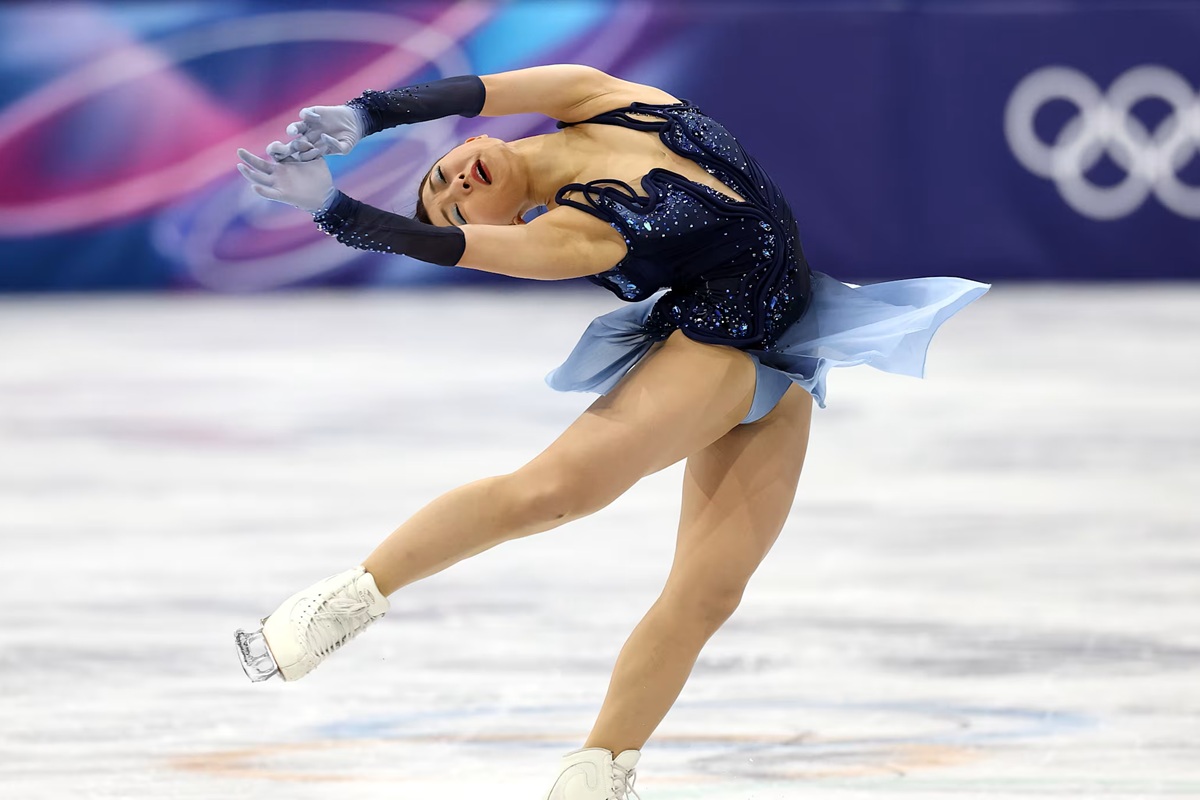 Atleta di pattinaggio di figura esegue una figura artistica sul ghiaccio durante le Olimpiadi Invernali.