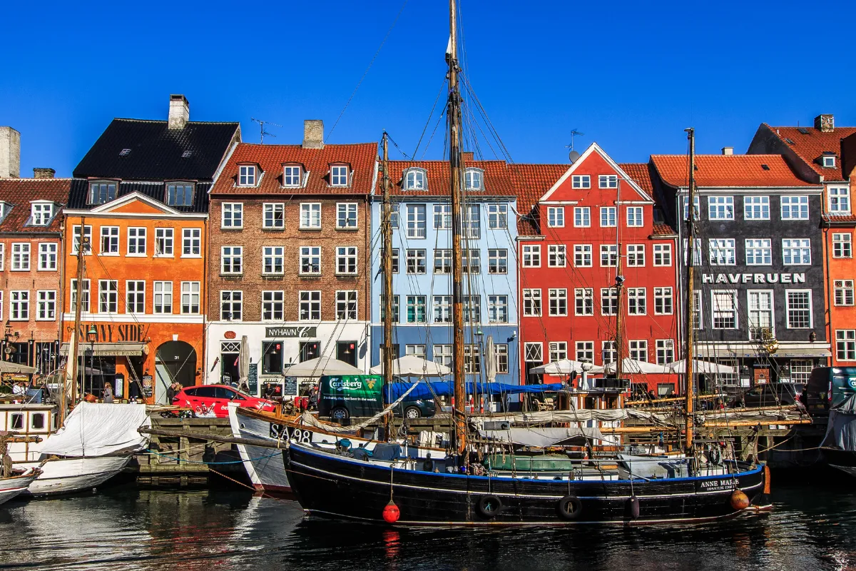 Una barca di legno attraccata di fronte alle case colorate del porto di Nyhavn a Copenaghen.