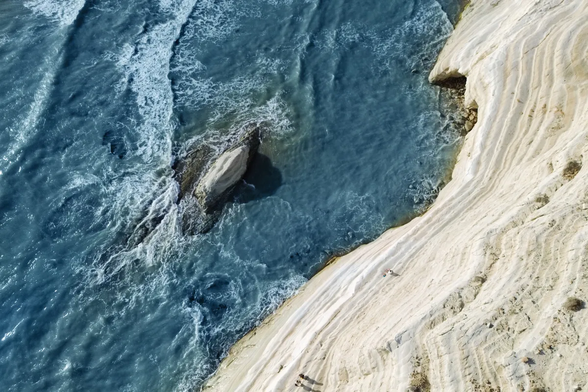 Vista aerea delle bianche scogliere di Scala dei Turchi con il mare azzurro che si infrange contro le rocce della costa siciliana.