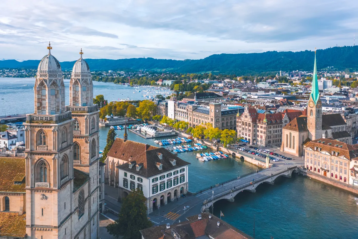 Veduta aerea di Zurigo con chiese storiche, il fiume Limmat, il ponte e le barche sul lago.