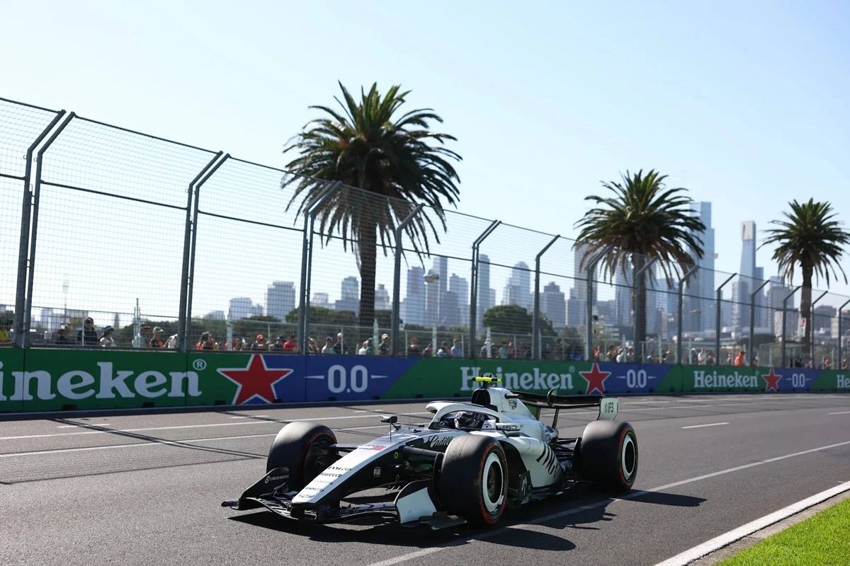 Auto di Formula 1 che corre su un circuito cittadino con palme, barriere di sicurezza e skyline urbano sullo sfondo