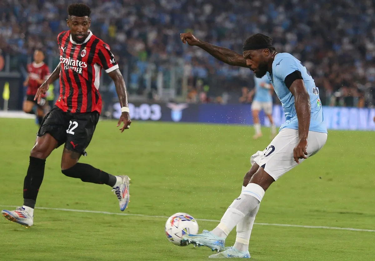 Calciatore della Lazio calcia il pallone durante una partita contro il Milan mentre un giocatore rossonero tenta di difendere