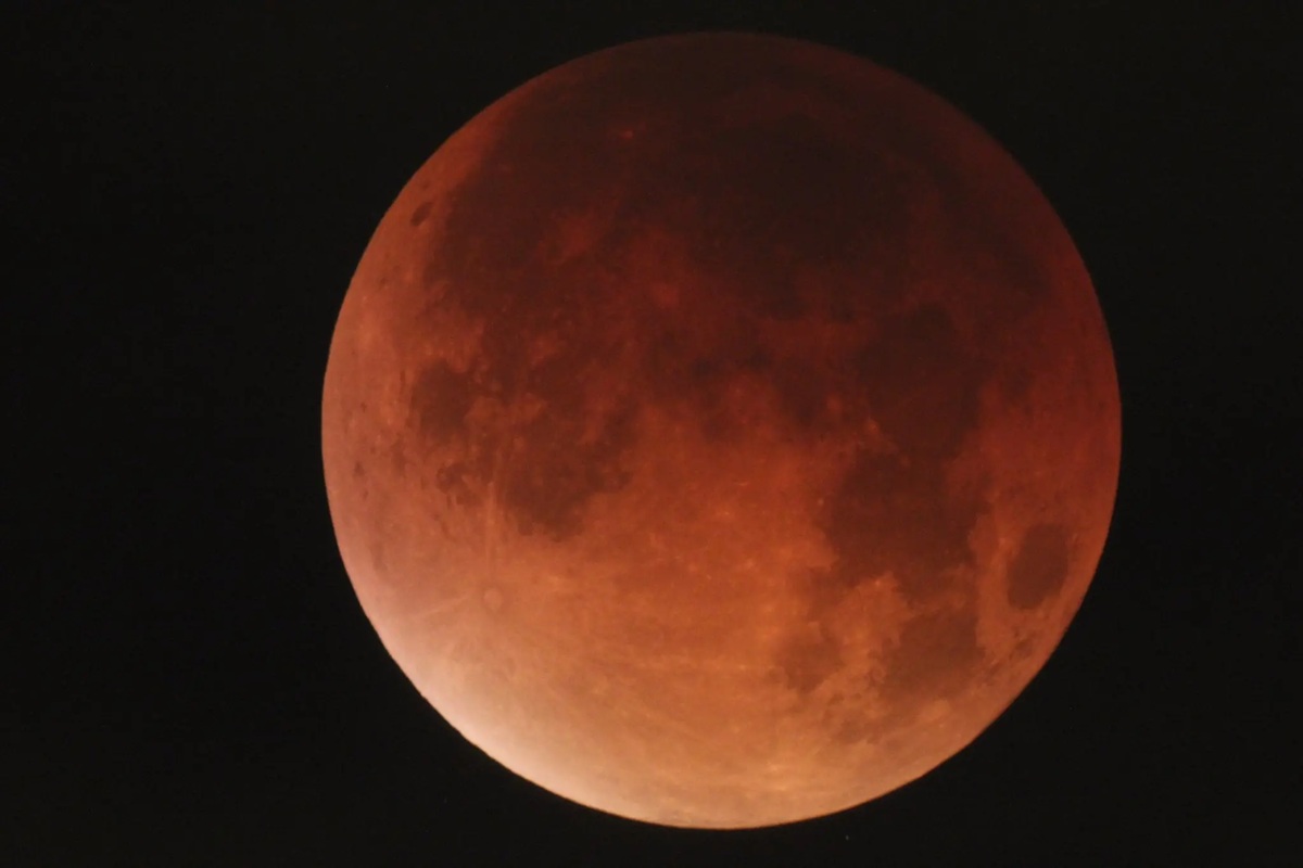 Luna di sangue rossa durante un’eclissi lunare totale su sfondo nero nel cielo notturno.