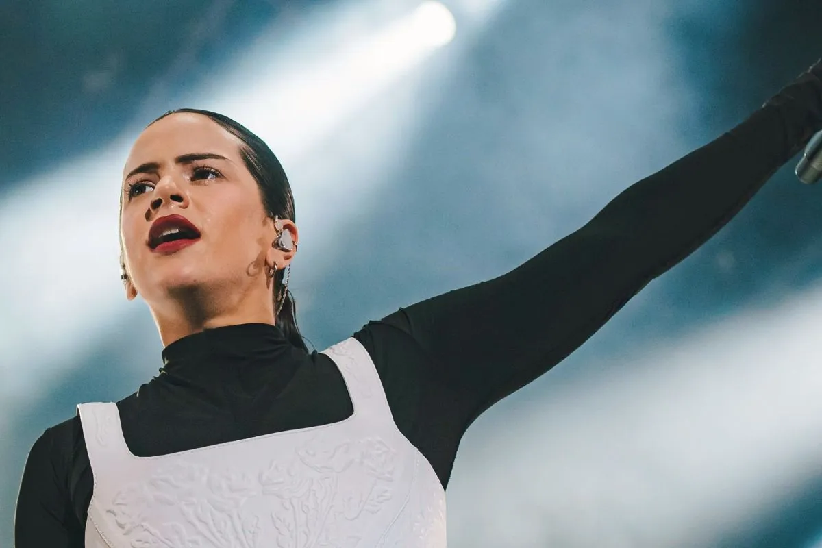 Cantante donna che si esibisce dal vivo su un palco illuminato, con braccio alzato e microfono