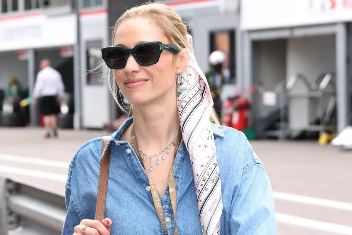 Donna bionda con occhiali da sole e camicia in denim in un contesto urbano
