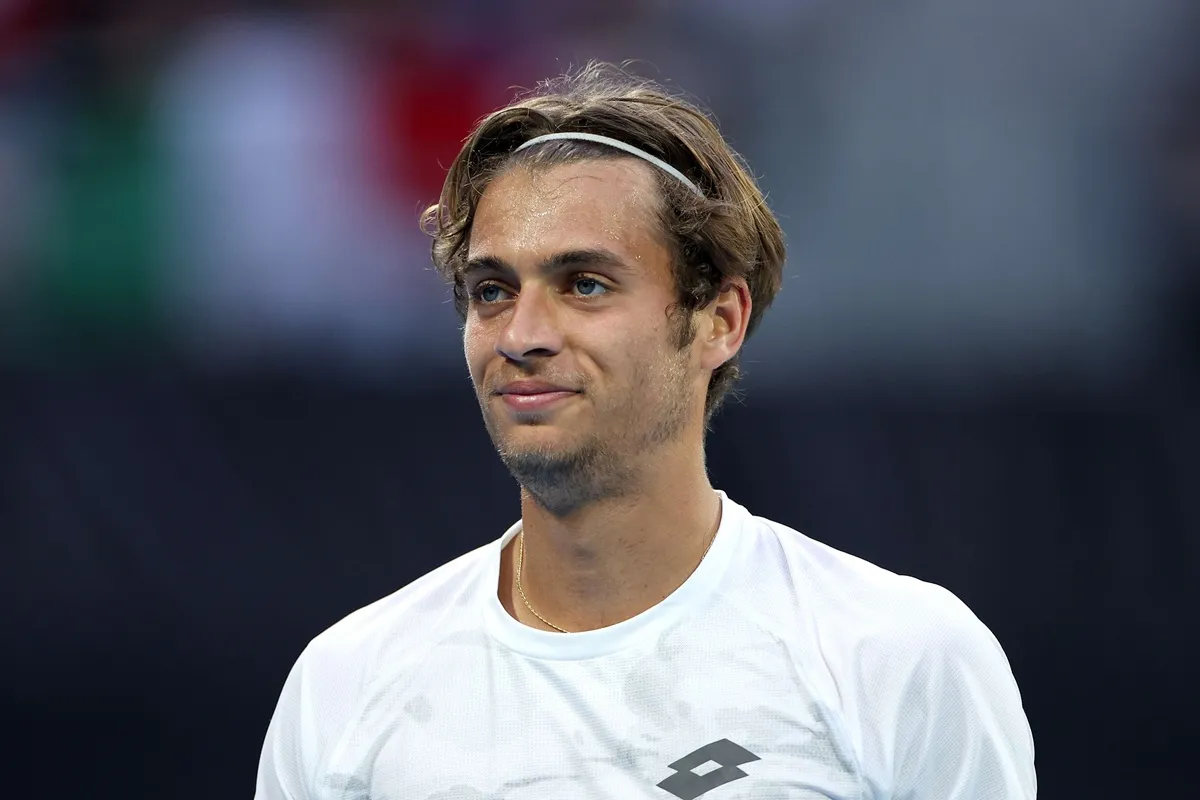 Tennista Flavio Cobolli con fascia nei capelli durante una partita, primo piano sul campo