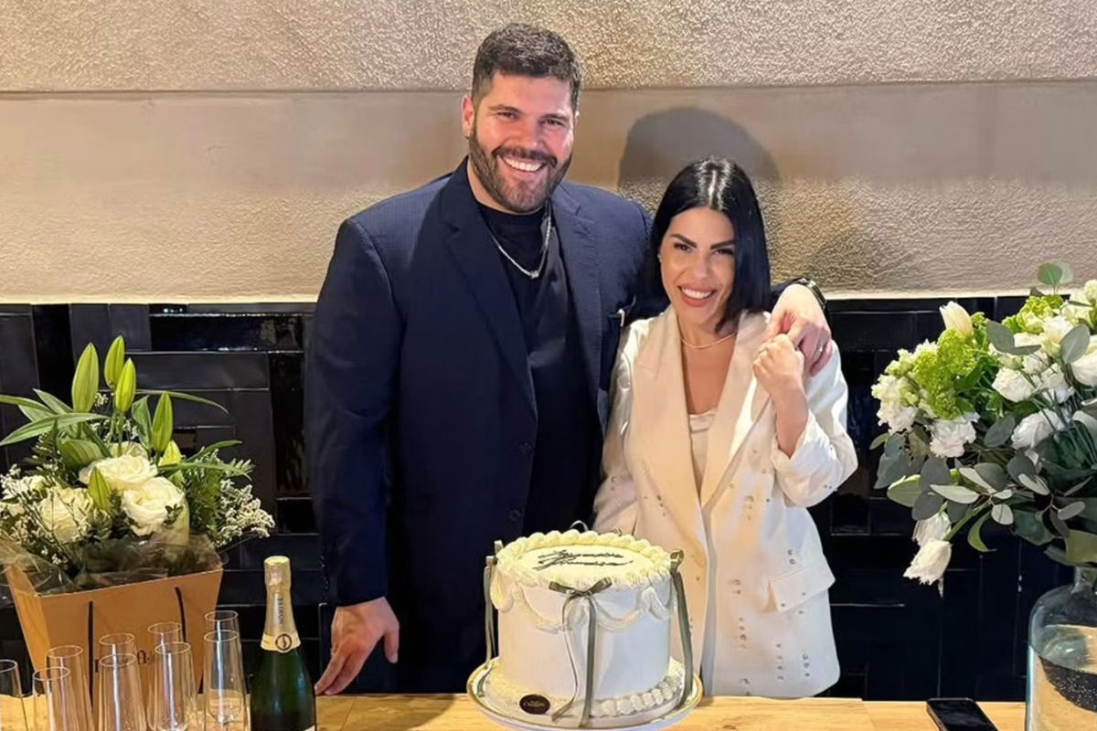 Coppia sorridente accanto a una torta decorata con champagne e fiori durante una celebrazione