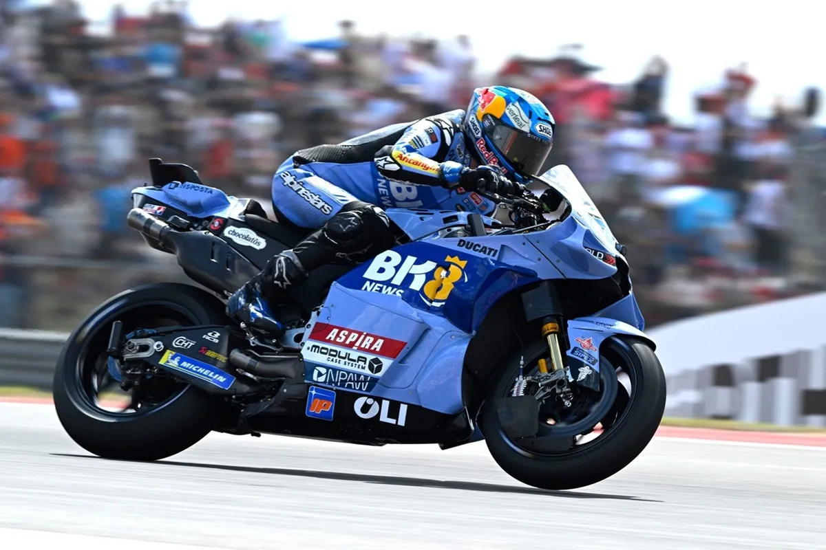 Pilota di MotoGP su moto Ducati blu affronta una curva ad alta velocità in pista