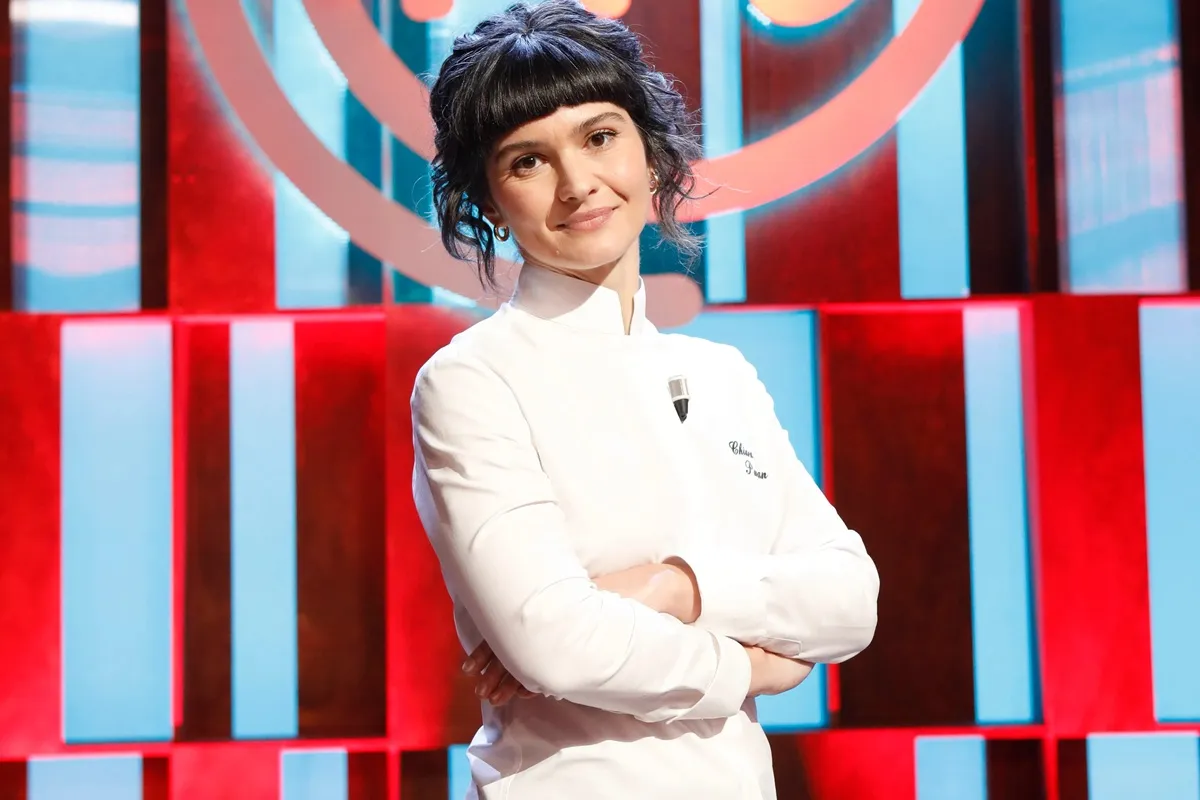Chef donna con uniforme bianca in studio culinario con sfondo colorato