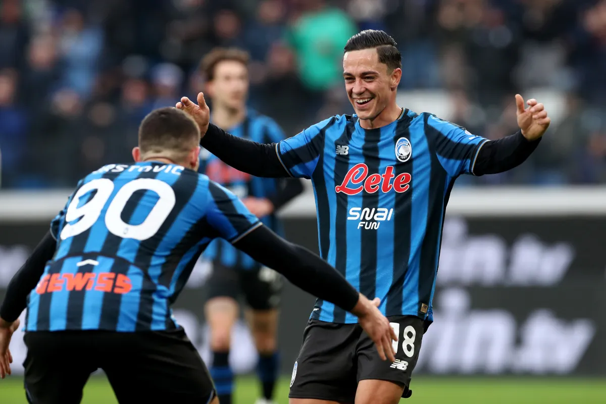 Giocatori dell’Atalanta in maglia nerazzurra festeggiano un gol durante una partita in uno stadio affollato