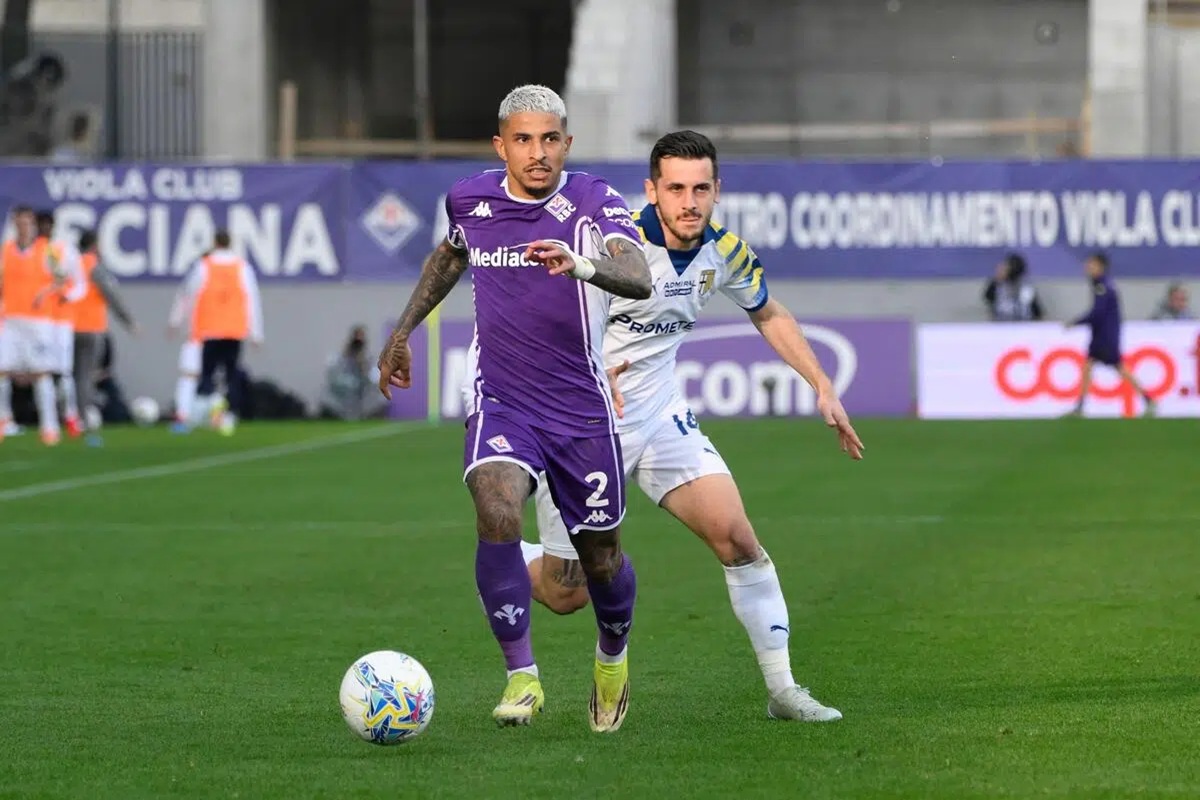 Calciatore della Fiorentina in maglia viola controlla il pallone mentre un avversario della Lazio lo insegue durante la partita