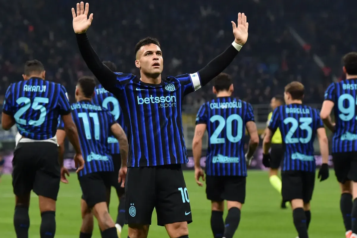 Calciatore dell’Inter con maglia nerazzurra alza le braccia mentre i compagni si allontanano sul campo da gioco