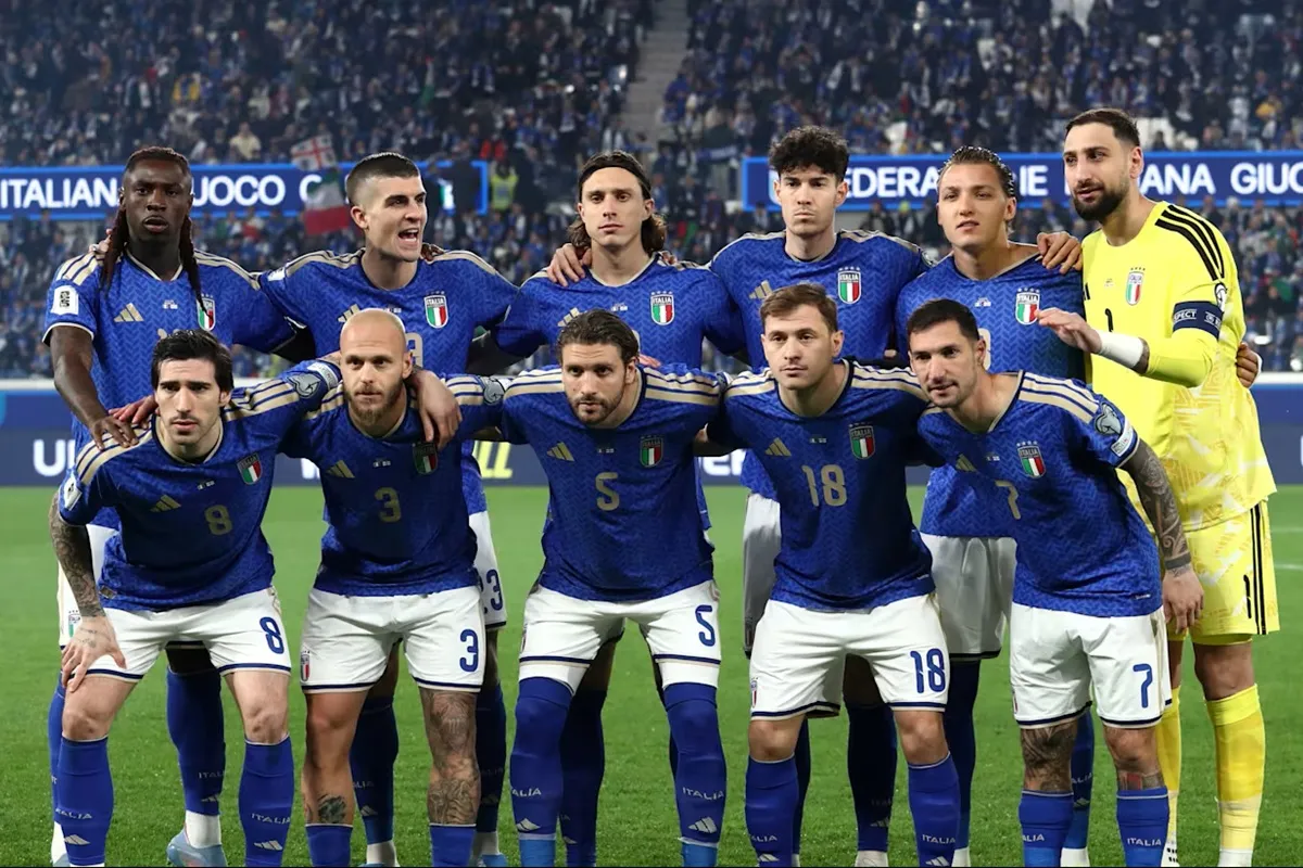 Giocatori della nazionale italiana di calcio posano insieme prima di una partita, con divisa blu e portiere in giallo