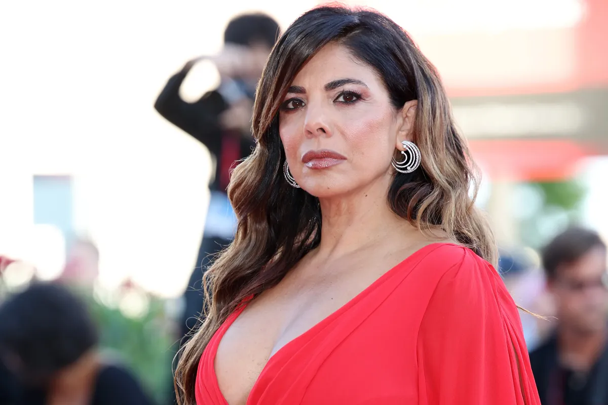 Donna elegante con abito rosso e orecchini vistosi posa su un red carpet durante un evento pubblico