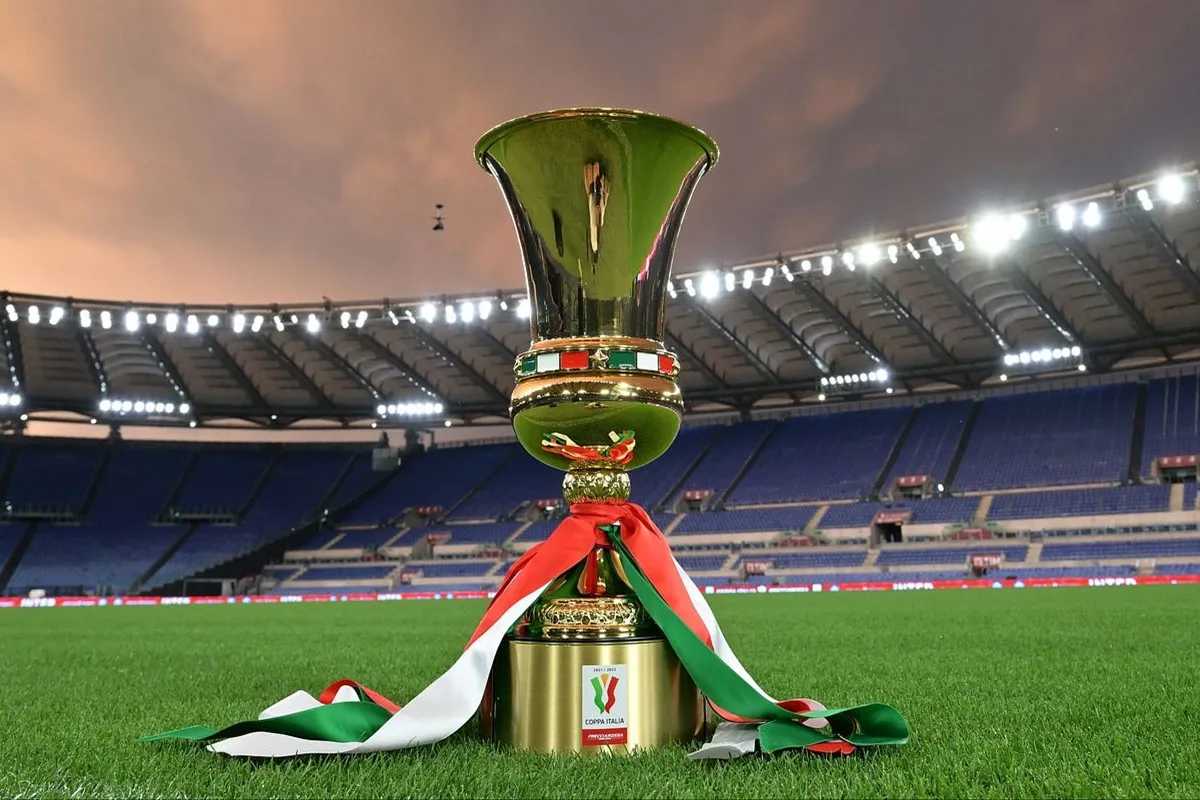 Trofeo della Coppa Italia posizionato sul campo da calcio in uno stadio illuminato prima della partita